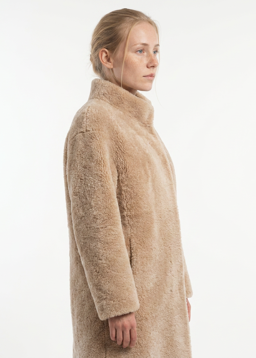 Model wearing the dark beige Filuka curly lamb coat with a high collar, side view