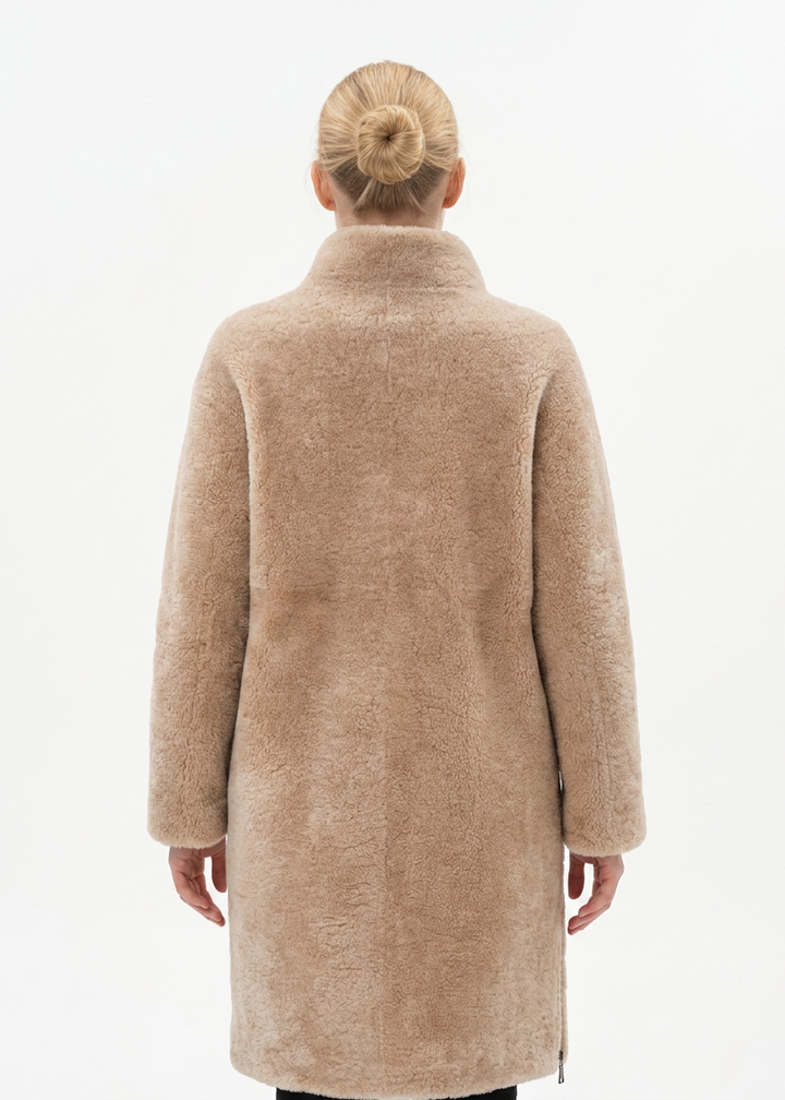 Model wearing the dark beige Filuka curly lamb coat with a high collar, back view
